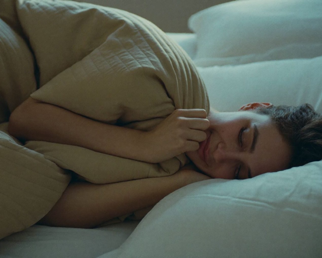 Heavy Sheep: a woman asleep under a sand-coloured weighted blanket